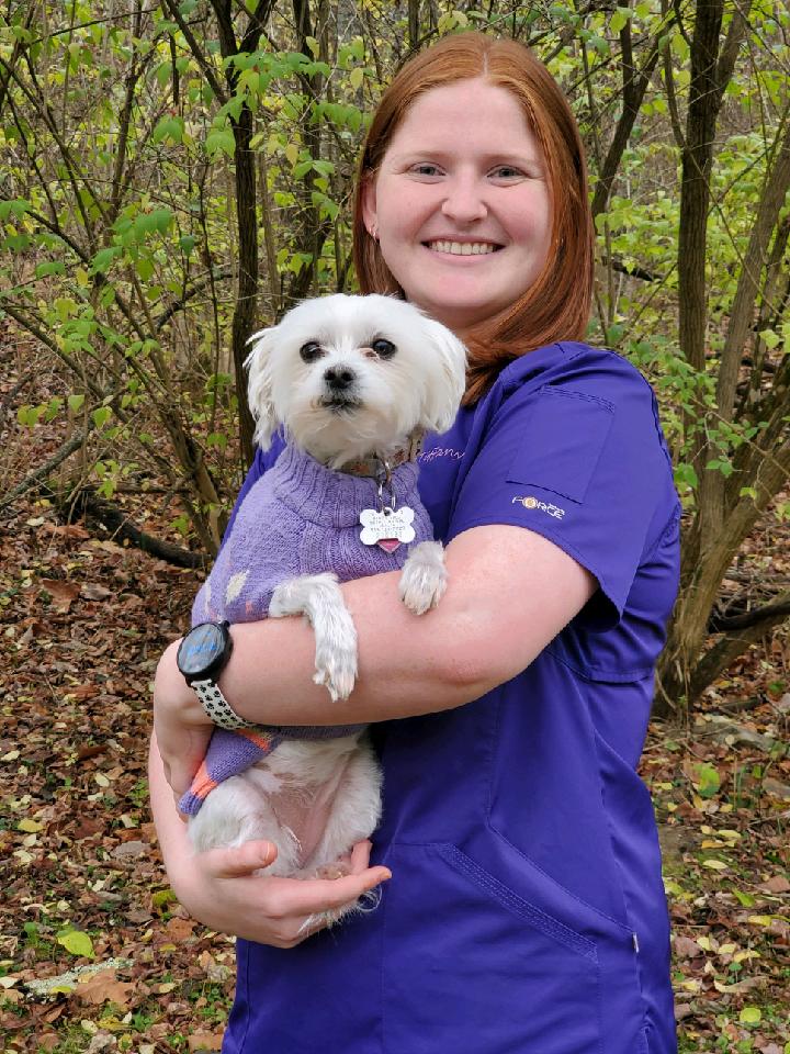 Tiffany holding a small dog in a sweater outside. Image from Beechmont Pet Hospital's old website.